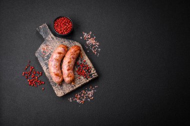 Lezzetli ızgara tavuk ya da koyu beton arka planda tuzlu ve baharatlı domuz sosisi.