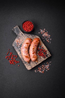 Lezzetli ızgara tavuk ya da koyu beton arka planda tuzlu ve baharatlı domuz sosisi.