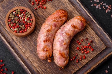 Lezzetli ızgara tavuk ya da koyu beton arka planda tuzlu ve baharatlı domuz sosisi.