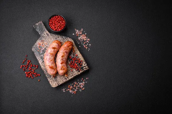 Lezzetli ızgara tavuk ya da koyu beton arka planda tuzlu ve baharatlı domuz sosisi.