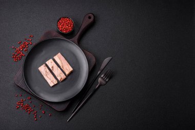 Lezzetli konserve ton balığı eti, tuz, baharat ve yağlı koyu beton arka planda.