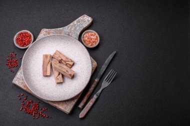 Lezzetli konserve ton balığı eti, tuz, baharat ve yağlı koyu beton arka planda.