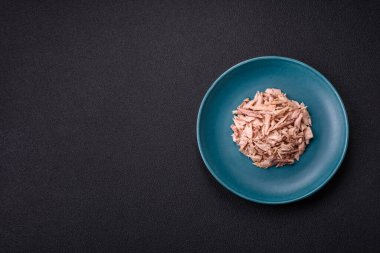 Lezzetli konserve ton balığı eti, tuz, baharat ve yağlı koyu beton arka planda.