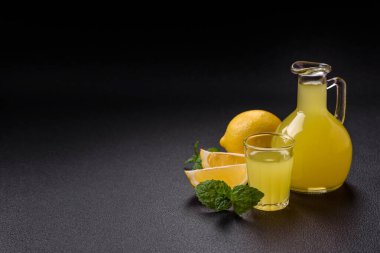 Alkolik sarı limoncello içer. Küçük bardakta, koyu beton arka planda.