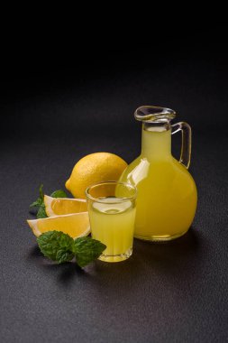 Alkolik sarı limoncello içer. Küçük bardakta, koyu beton arka planda.