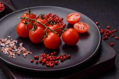 Koyu arkaplanda tuzlu ve baharatlı çiğ domates dalıyla. Evde yemek pişirmek için gerekli malzemeler