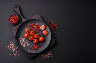 Koyu arkaplanda tuzlu ve baharatlı çiğ domates dalıyla. Evde yemek pişirmek için gerekli malzemeler