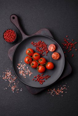 Koyu arkaplanda tuzlu ve baharatlı çiğ domates dalıyla. Evde yemek pişirmek için gerekli malzemeler