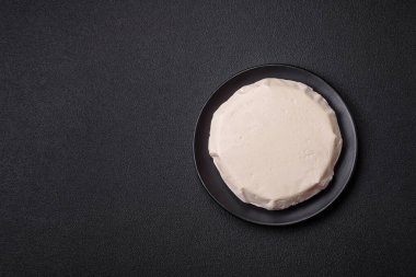 Koyu beton bir arka planda inek sütü veya koyun sütünden taze taze, lezzetli beyaz peynir.