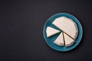 Koyu beton bir arka planda inek sütü veya koyun sütünden taze taze, lezzetli beyaz peynir.