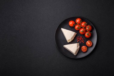 Koyu beton bir arka planda inek sütü veya koyun sütünden taze taze, lezzetli beyaz peynir.