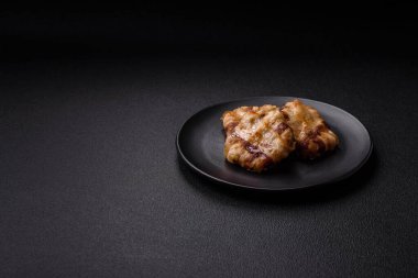 Koyu beton bir arka planda tuzlu, baharatlı ve otlu domuz pastırmasına sarılı yuvarlak doğranmış tavuk veya domuz pirzolası.