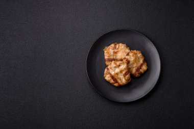 Koyu beton bir arka planda tuzlu, baharatlı ve otlu domuz pastırmasına sarılı yuvarlak doğranmış tavuk veya domuz pirzolası.