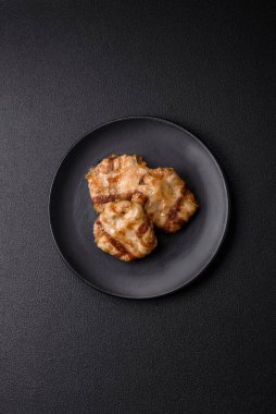 Koyu beton bir arka planda tuzlu, baharatlı ve otlu domuz pastırmasına sarılı yuvarlak doğranmış tavuk veya domuz pirzolası.