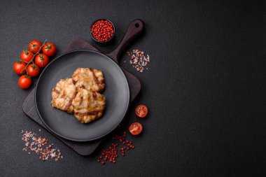 Koyu beton bir arka planda tuzlu, baharatlı ve otlu domuz pastırmasına sarılı yuvarlak doğranmış tavuk veya domuz pirzolası.