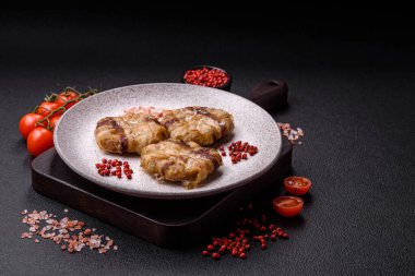 Koyu beton bir arka planda tuzlu, baharatlı ve otlu domuz pastırmasına sarılı yuvarlak doğranmış tavuk veya domuz pirzolası.