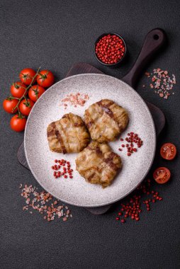 Koyu beton bir arka planda tuzlu, baharatlı ve otlu domuz pastırmasına sarılı yuvarlak doğranmış tavuk veya domuz pirzolası.