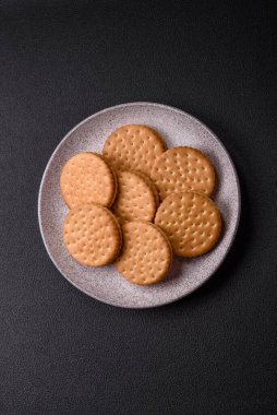 Koyu beton arka planda kremalı yuvarlak atıştırmalık kurabiyeler. Kahvaltıda tatlı.