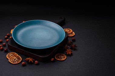 Empty ceramic round plate on dark textured concrete background. Cutlery, preparation for dinner