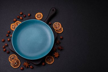 Empty ceramic round plate on dark textured concrete background. Cutlery, preparation for dinner