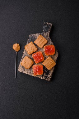 Fıstık ezmeli lezzetli, besleyici sandviçler, koyu beton arka planda çilek reçeli.