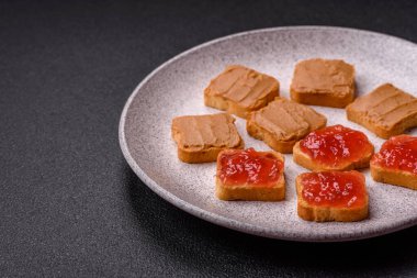 Fıstık ezmeli lezzetli, besleyici sandviçler, koyu beton arka planda çilek reçeli.