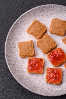 Fıstık ezmeli lezzetli, besleyici sandviçler, koyu beton arka planda çilek reçeli.