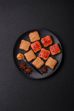 Fıstık ezmeli lezzetli, besleyici sandviçler, koyu beton arka planda çilek reçeli.