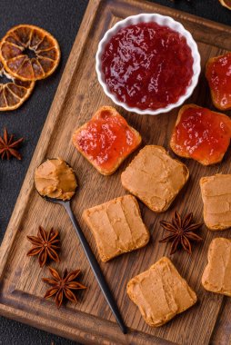 Fıstık ezmeli lezzetli, besleyici sandviçler, koyu beton arka planda çilek reçeli.