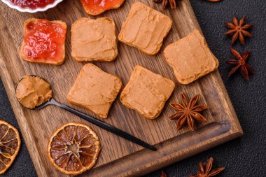 Fıstık ezmeli lezzetli, besleyici sandviçler, koyu beton arka planda çilek reçeli.