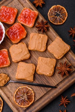 Fıstık ezmeli lezzetli, besleyici sandviçler, koyu beton arka planda çilek reçeli.