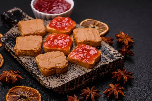 Fıstık ezmeli lezzetli, besleyici sandviçler, koyu beton arka planda çilek reçeli.