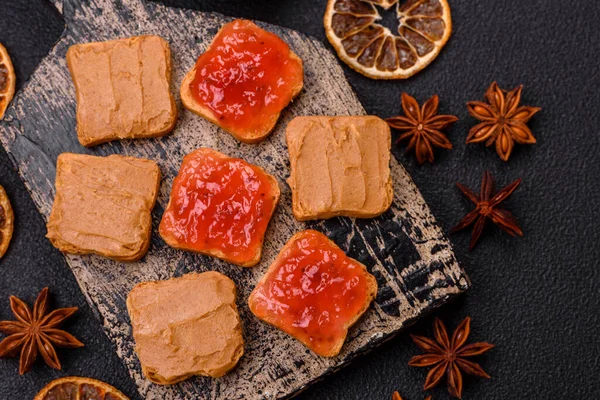 Fıstık ezmeli lezzetli, besleyici sandviçler, koyu beton arka planda çilek reçeli.