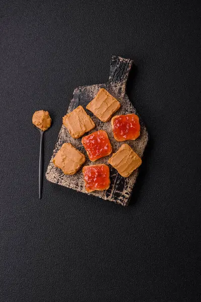 Fıstık ezmeli lezzetli, besleyici sandviçler, koyu beton arka planda çilek reçeli.