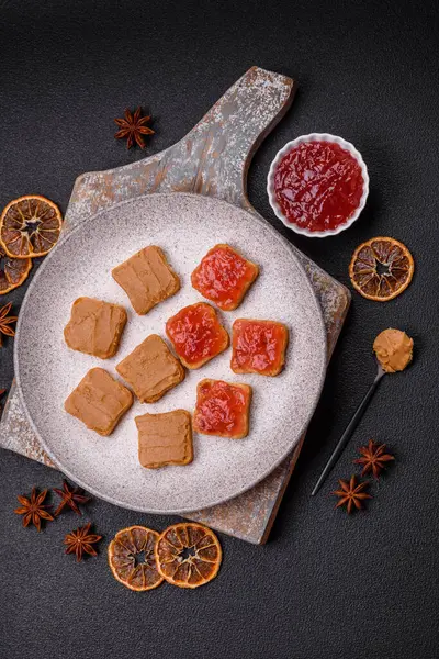 Fıstık ezmeli lezzetli, besleyici sandviçler, koyu beton arka planda çilek reçeli.