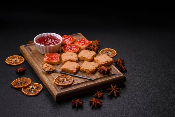 Fıstık ezmeli lezzetli, besleyici sandviçler, koyu beton arka planda çilek reçeli.