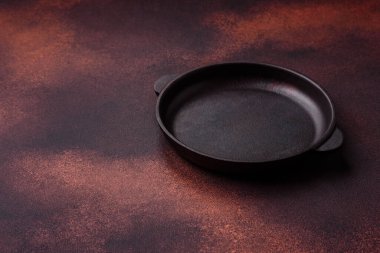 Empty ceramic round plate on dark textured concrete background. Cutlery, preparation for dinner