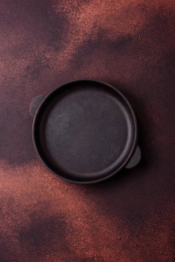 Empty ceramic round plate on dark textured concrete background. Cutlery, preparation for dinner