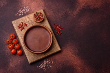 Empty ceramic round plate on dark textured concrete background. Cutlery, preparation for dinner