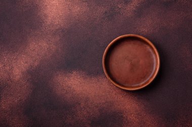 Empty ceramic round plate on dark textured concrete background. Cutlery, preparation for dinner