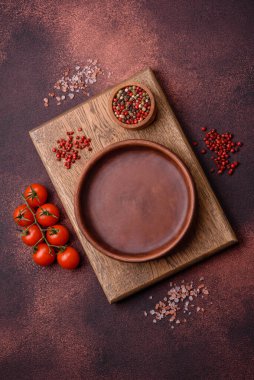 Empty ceramic round plate on dark textured concrete background. Cutlery, preparation for dinner