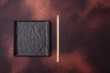Koyu beton zemin üzerinde boş siyah kare seramik plaka. Asya yemeği pişirmek