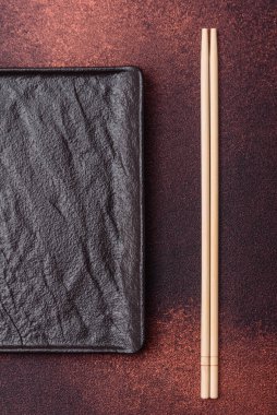 Koyu beton zemin üzerinde boş siyah kare seramik plaka. Asya yemeği pişirmek