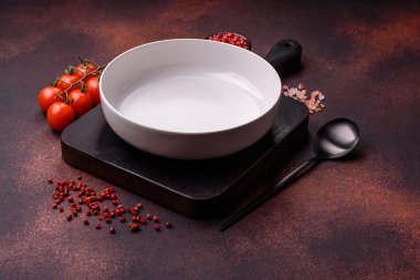 Empty ceramic round plate on dark textured concrete background. Cutlery, preparation for dinner