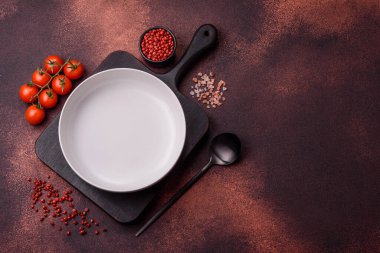Empty ceramic round plate on dark textured concrete background. Cutlery, preparation for dinner