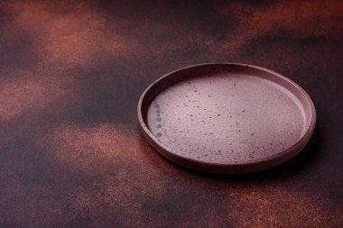 Empty ceramic round plate on dark textured concrete background. Cutlery, preparation for dinner