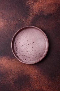 Empty ceramic round plate on dark textured concrete background. Cutlery, preparation for dinner