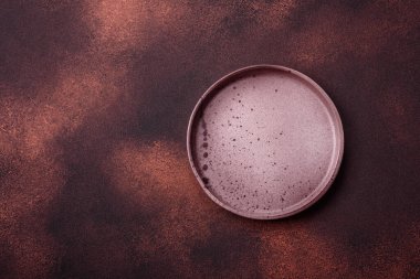 Empty ceramic round plate on dark textured concrete background. Cutlery, preparation for dinner