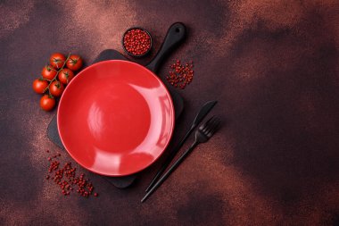 Empty ceramic round plate on dark textured concrete background. Cutlery, preparation for dinner