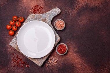Empty ceramic round plate on dark textured concrete background. Cutlery, preparation for dinner